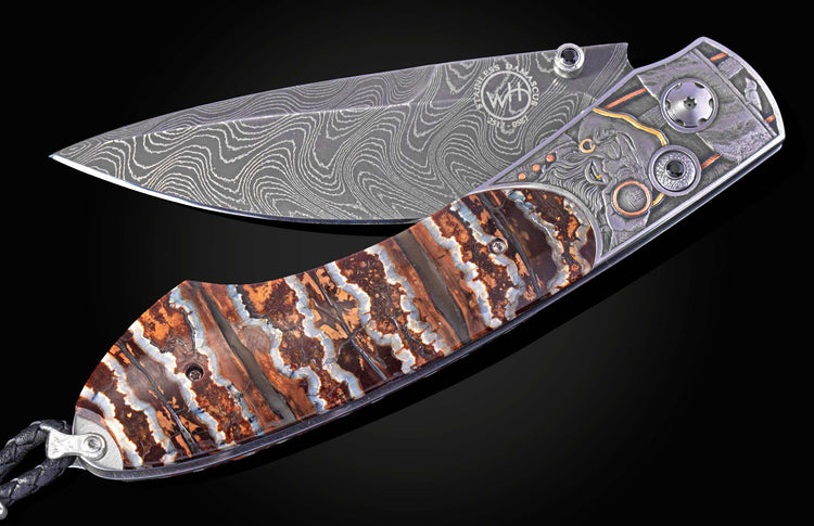 Folding knife with a wavy Damascus steel blade, engraved handle featuring a stylized face, and colorful banded fossil scales.