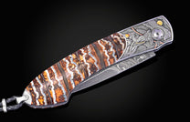 Custom folding knife with banded brown and orange agate handle scales, Damascus blade, and detailed pirate-themed engraving.