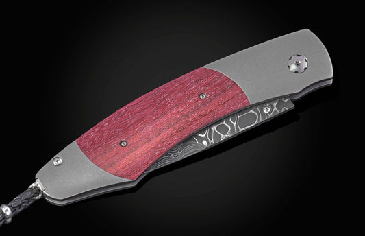 Folding knife with a purple heart wood handle and damascus blade on a black background