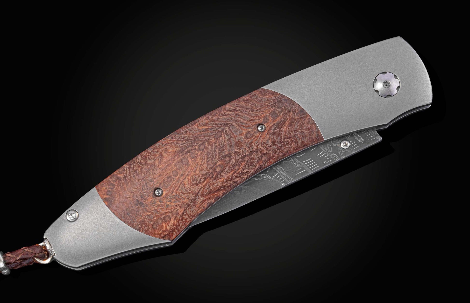 Folding knife with redwood handle and damascus blade closed on a black background 
