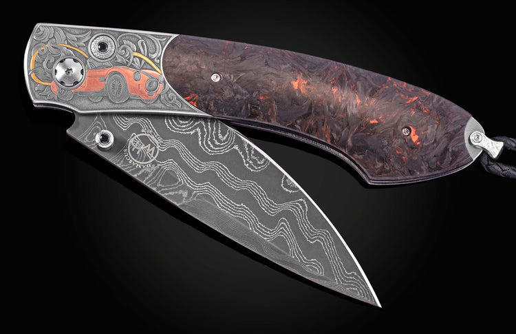 Open folding knife with a Damascus steel blade featuring 'WH DAMASCUS', and an engraved handle depicting a red Shelby Cobra car, scrollwork, and dark, fiery resin.