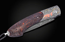Custom folding knife with a marbled reddish-brown handle, engraved silver bolster featuring an orange Shelby Cobra, and a damascus blade.