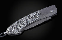 Hand carved silver folding knife with damascus steel on a black background
