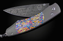 Decorative knife with colorful handle and damascus blade on a black background