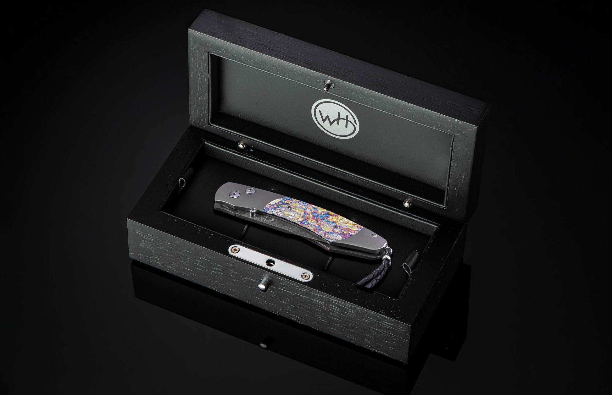 Decorative knife with colorful handle and damascus blade in wooden case on a black background