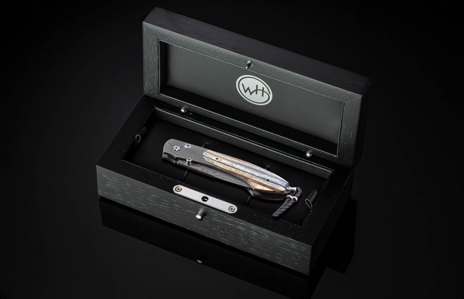 Folding knife in a black box with WH logo on a dark background