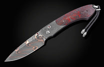 Folding knife with a Damascus blade, a red and black marbled handle, red gemstone accents, and a braided black leather lanyard.