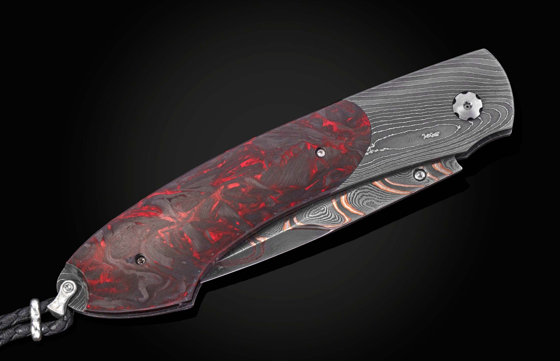 Folding knife with a red and black marbled handle, intricate Damascus steel frame and blade, and a black braided lanyard.