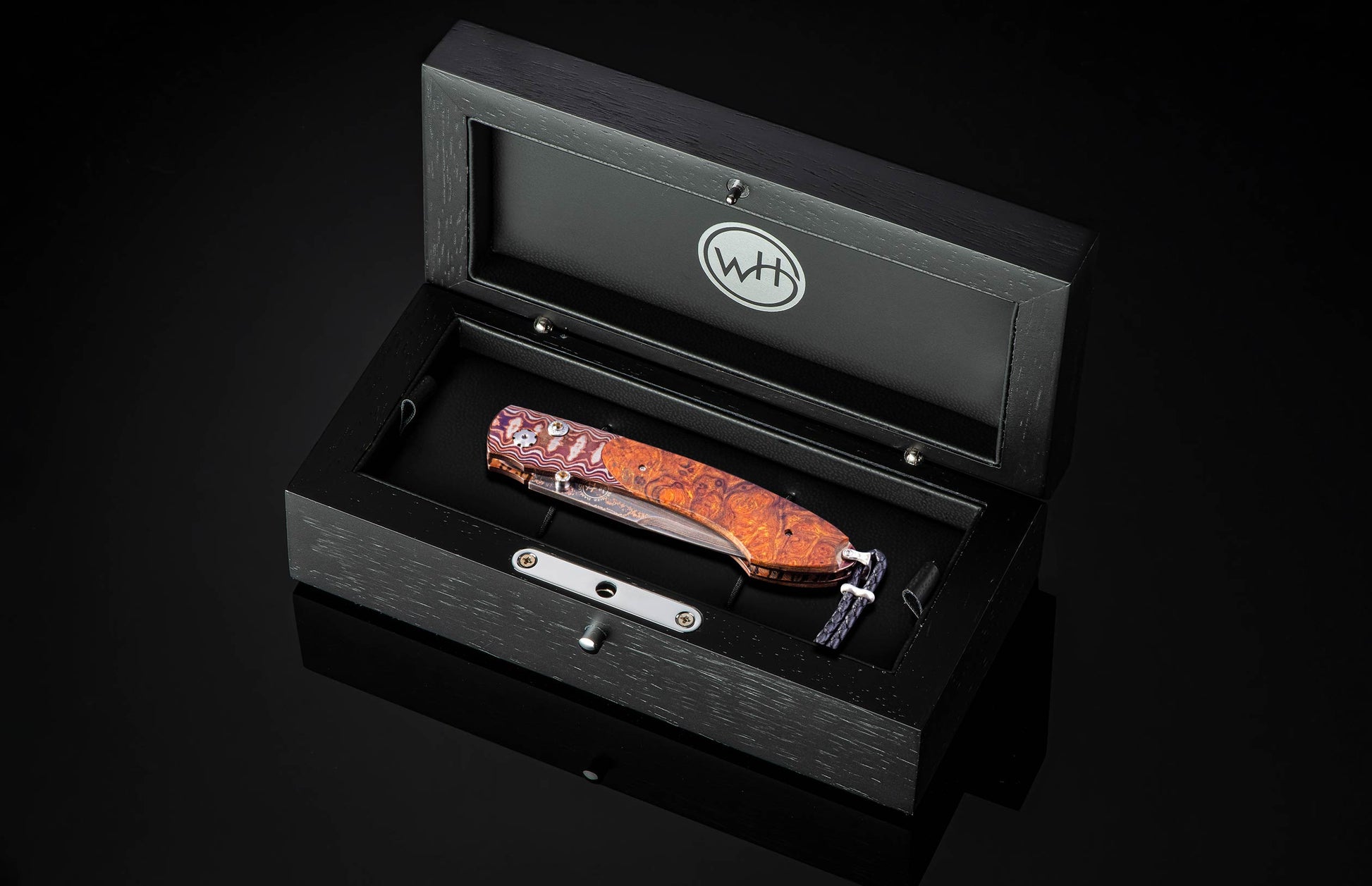 Folding knife with wooden handle in a black display box on a dark background