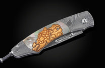 Decorative folding knife with artistic blade and embellishments on a dark background