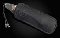 Decorative folding knife with artistic blade and embellishments on a dark background