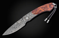 Damascus steel knife with intricate quail engraving and burl wood handle by B12, featuring silver hardware and braided lanyard, side view on black background