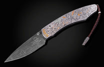 Decorative folding knife engraved with images from the Alamo on a black background