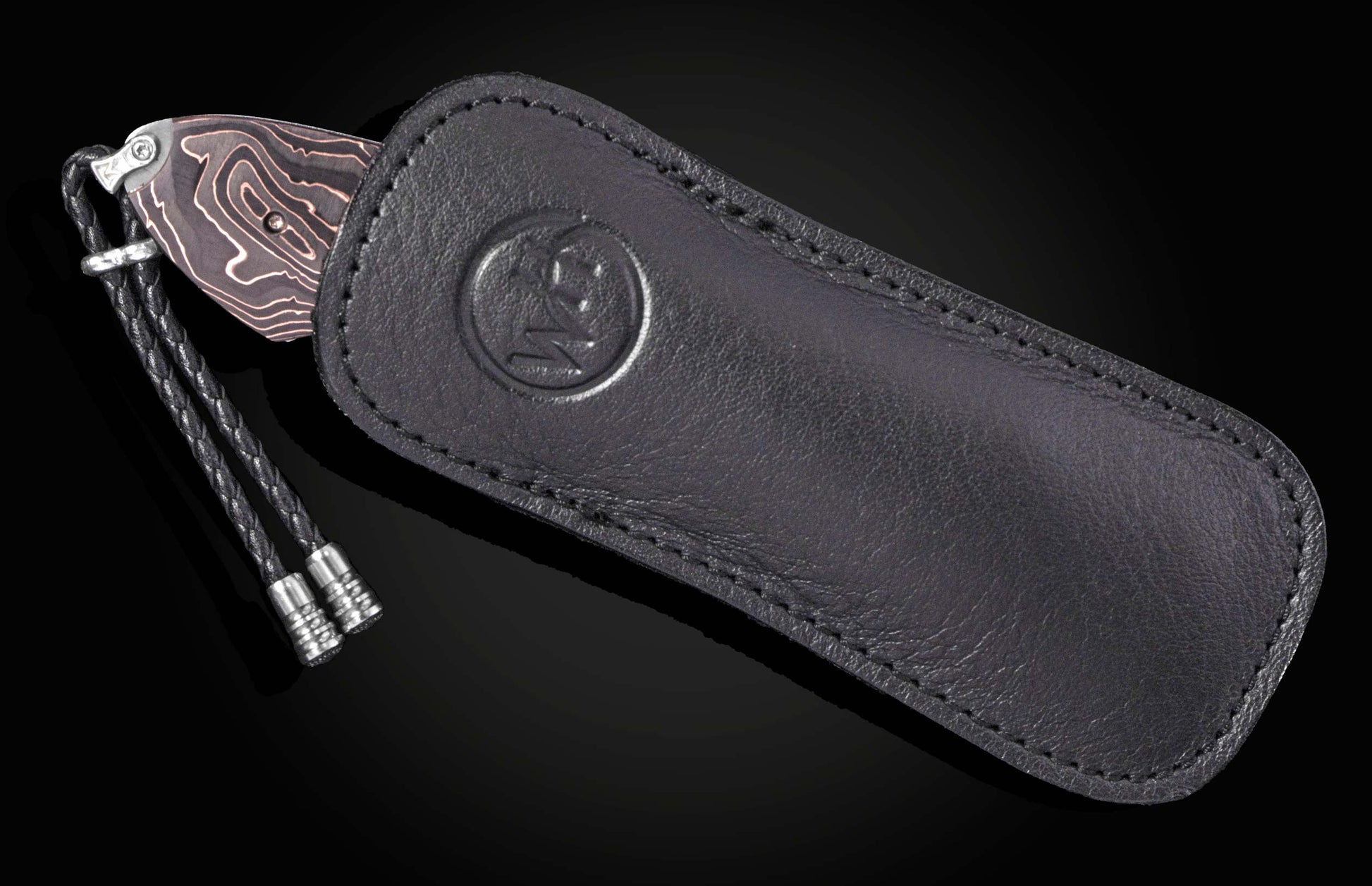 Western-style knife with patterned blade and black leather sheath by B12 WR, featuring embossed logo and braided lanyard, side view