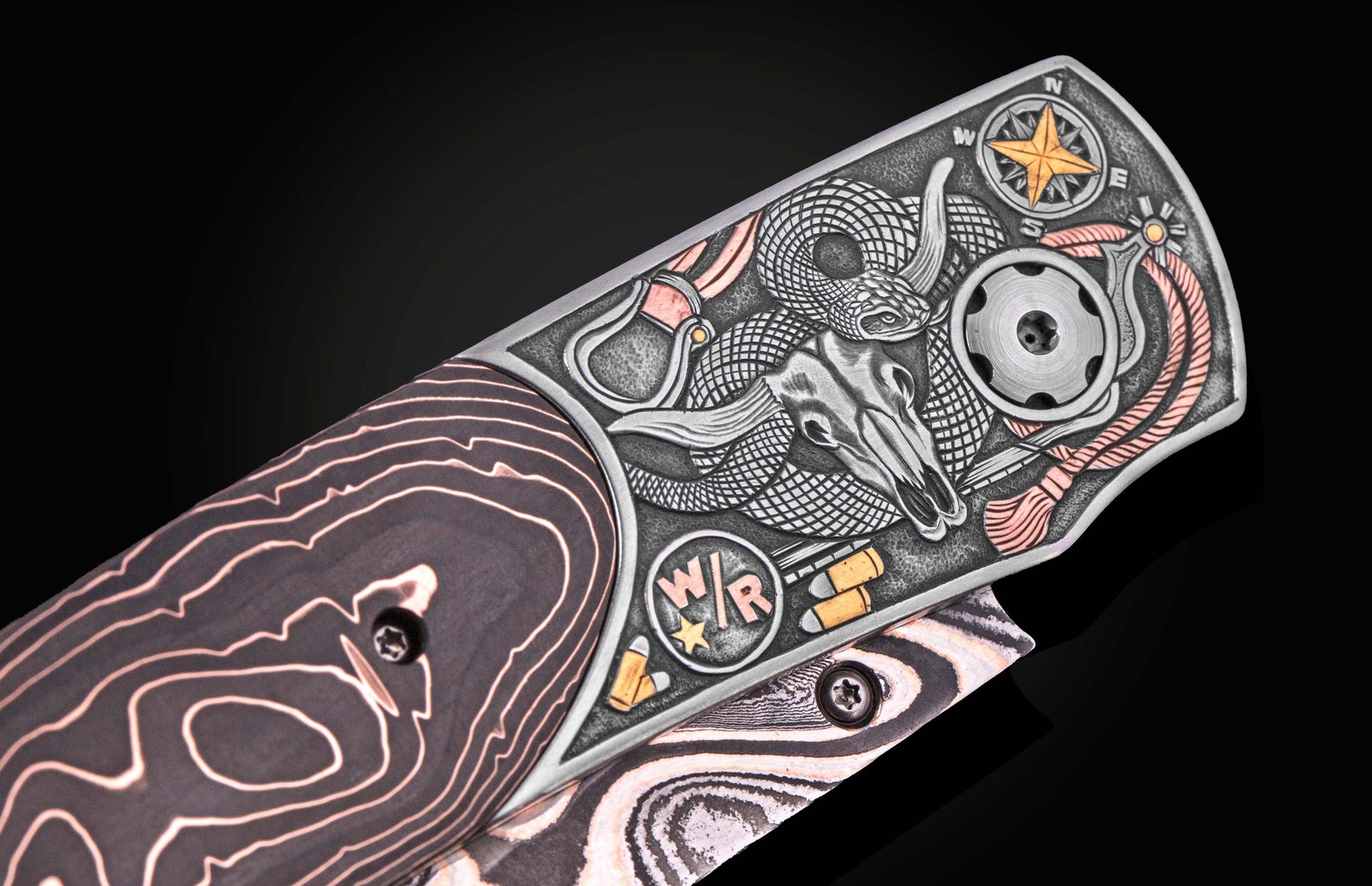 Western-style knife with engraved bull skull, snake, and compass design, featuring rose gold accents and layered wood handle, side view close-up