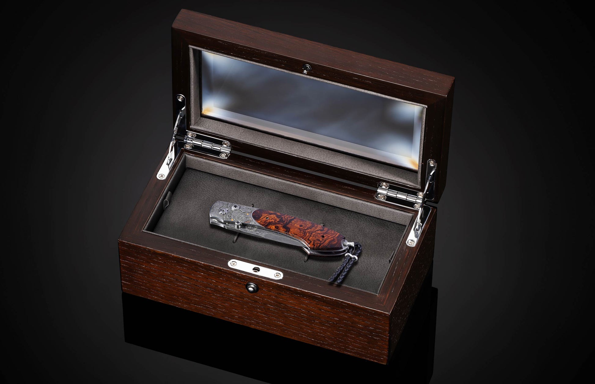 Folding knife with Damascus steel blade , hand engraving, and desert ironwood handle on a black background