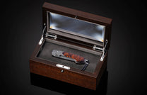 Folding knife with Damascus steel blade , hand engraving, and desert ironwood handle on a black background