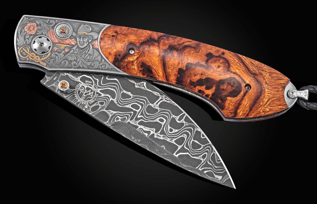 Luxury folding knife with damascus steel blade and burl wood handle, featuring engraved cowboy motif and gemstone accents, side view.
