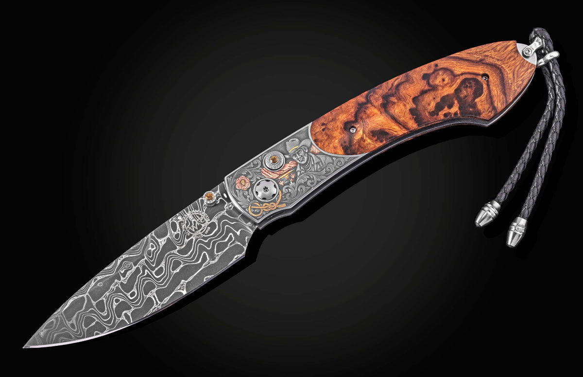 Damascus steel knife with burl wood handle by B12, featuring engraved cowboy motif and braided cord lanyard, side view on black background