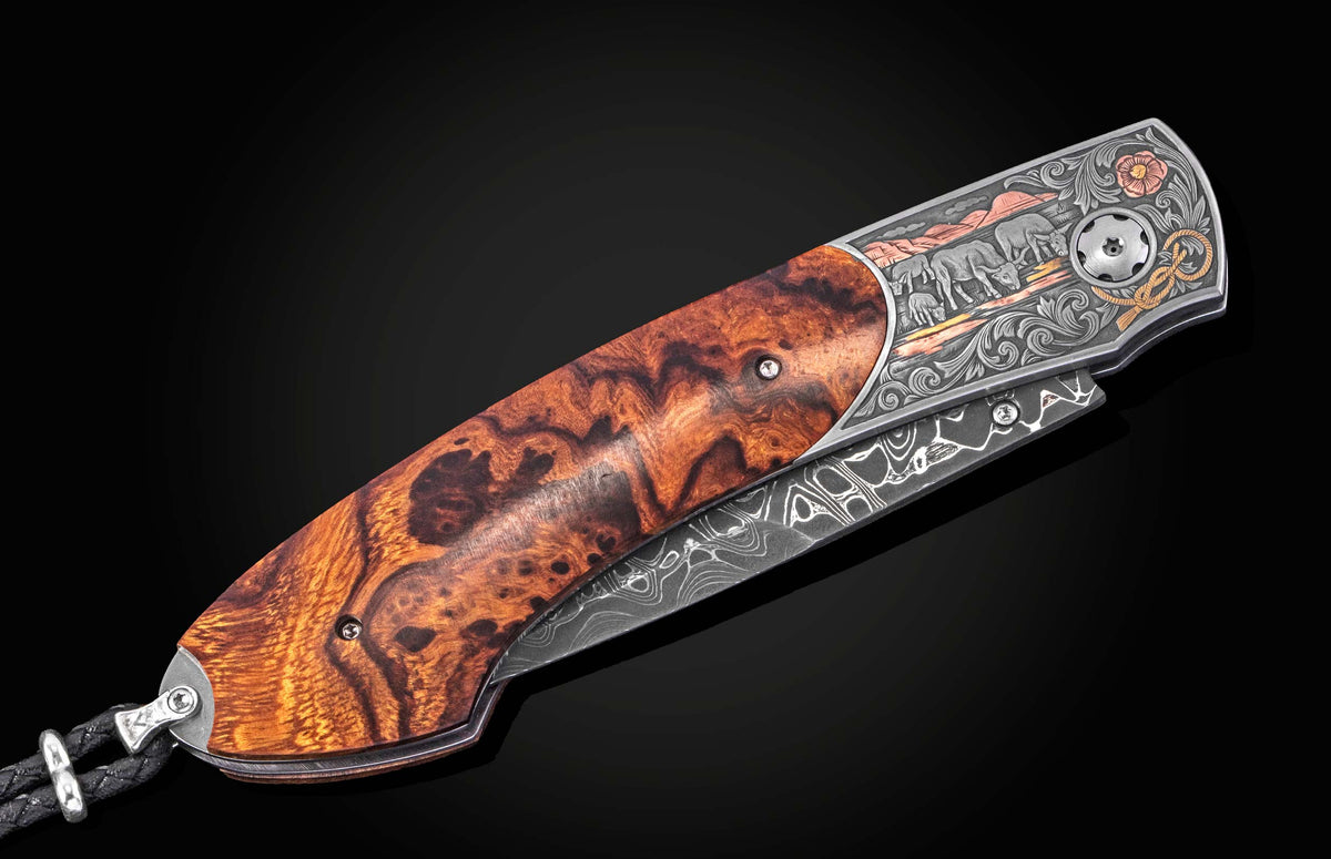 Luxury folding knife with burl wood handle and damascus blade, by B12, featuring engraved wildlife scene and floral accents, side view on black background