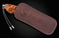 Luxury B12 Wrangler knife with rich wood grain handle, partially sheathed in dark brown leather with embossed logo and braided cord lanyard, side view.