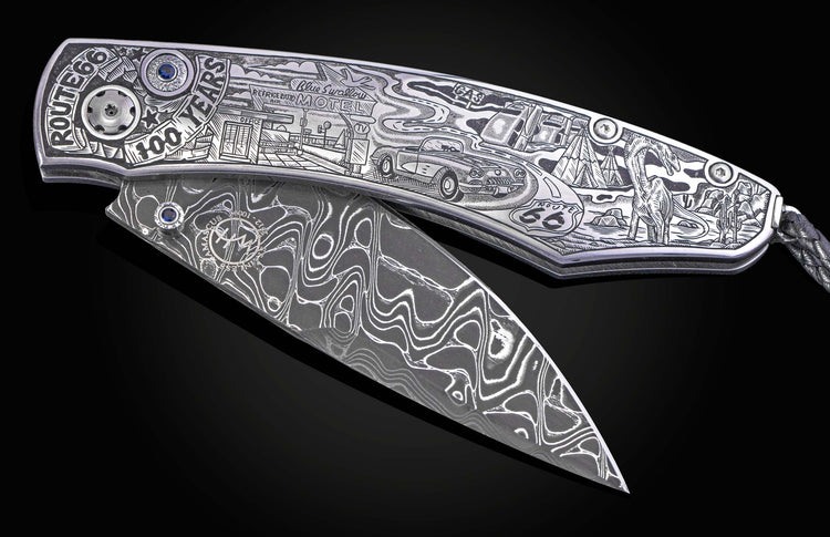 Engraved folding knife featuring Route 66 anniversary artwork on a silver handle, with a Damascus blade and blue gems.