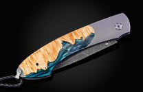 William Henry knife with a damascus steel blade and shockwood handle on a black background