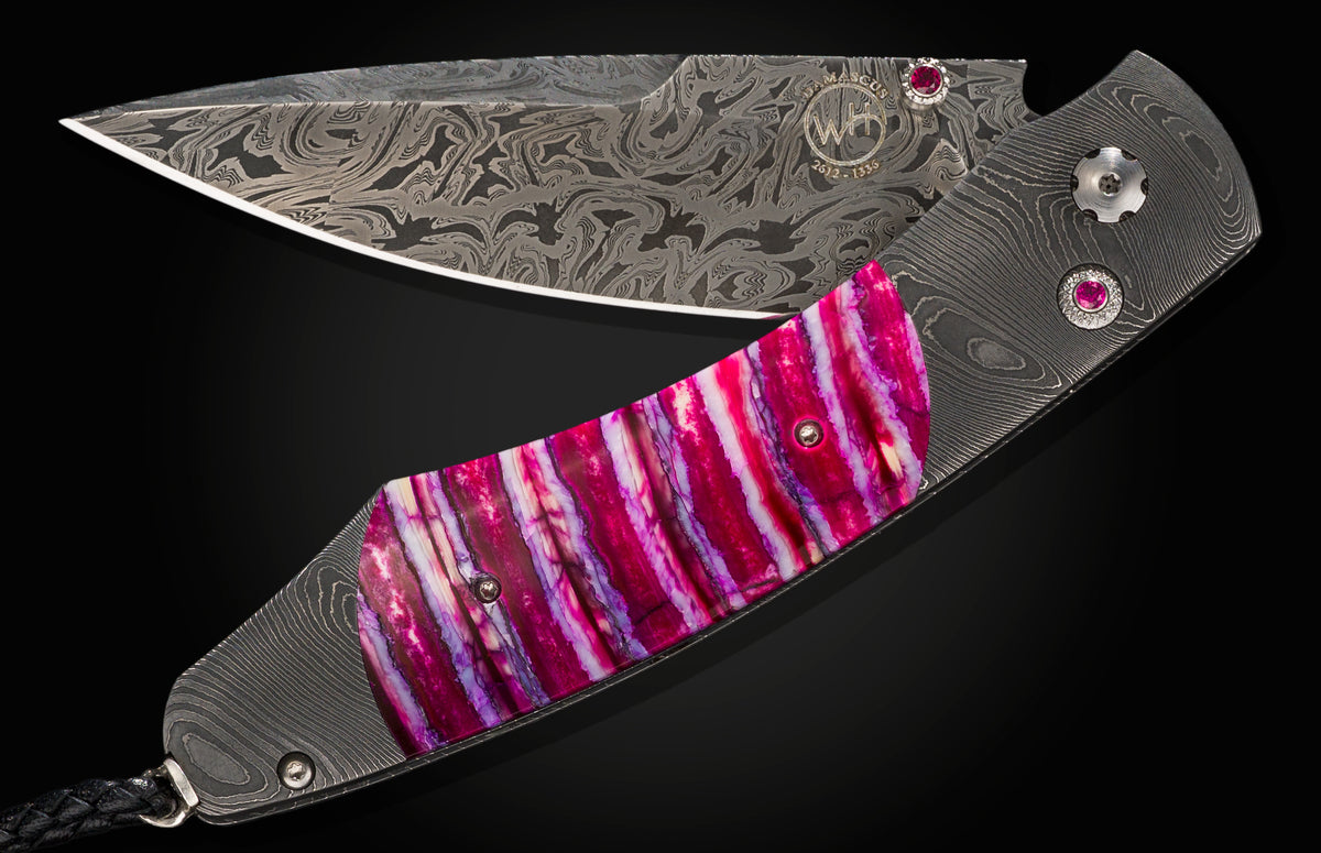 Damascus folding knife by B12 Hope, featuring a vibrant magenta inlay and ruby accents.