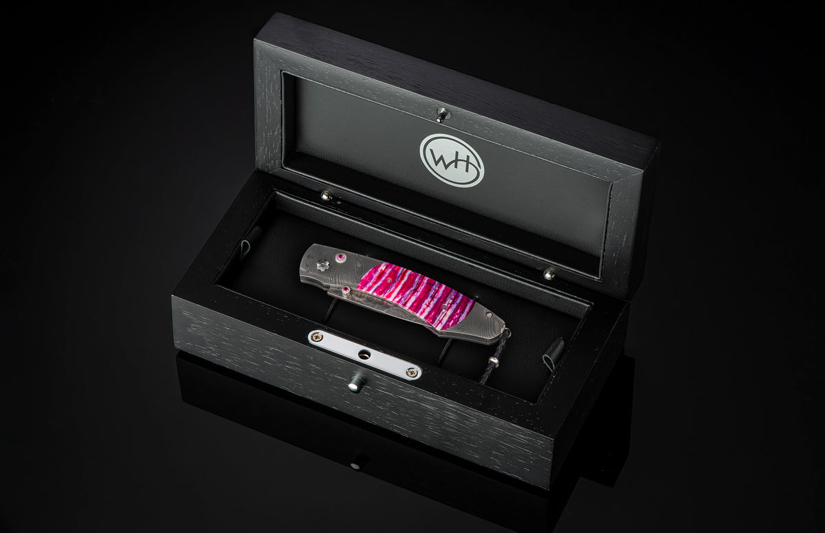 Luxury folding knife with vibrant pink and purple resin inlays by B12 Hope, displayed in a sleek black presentation case.