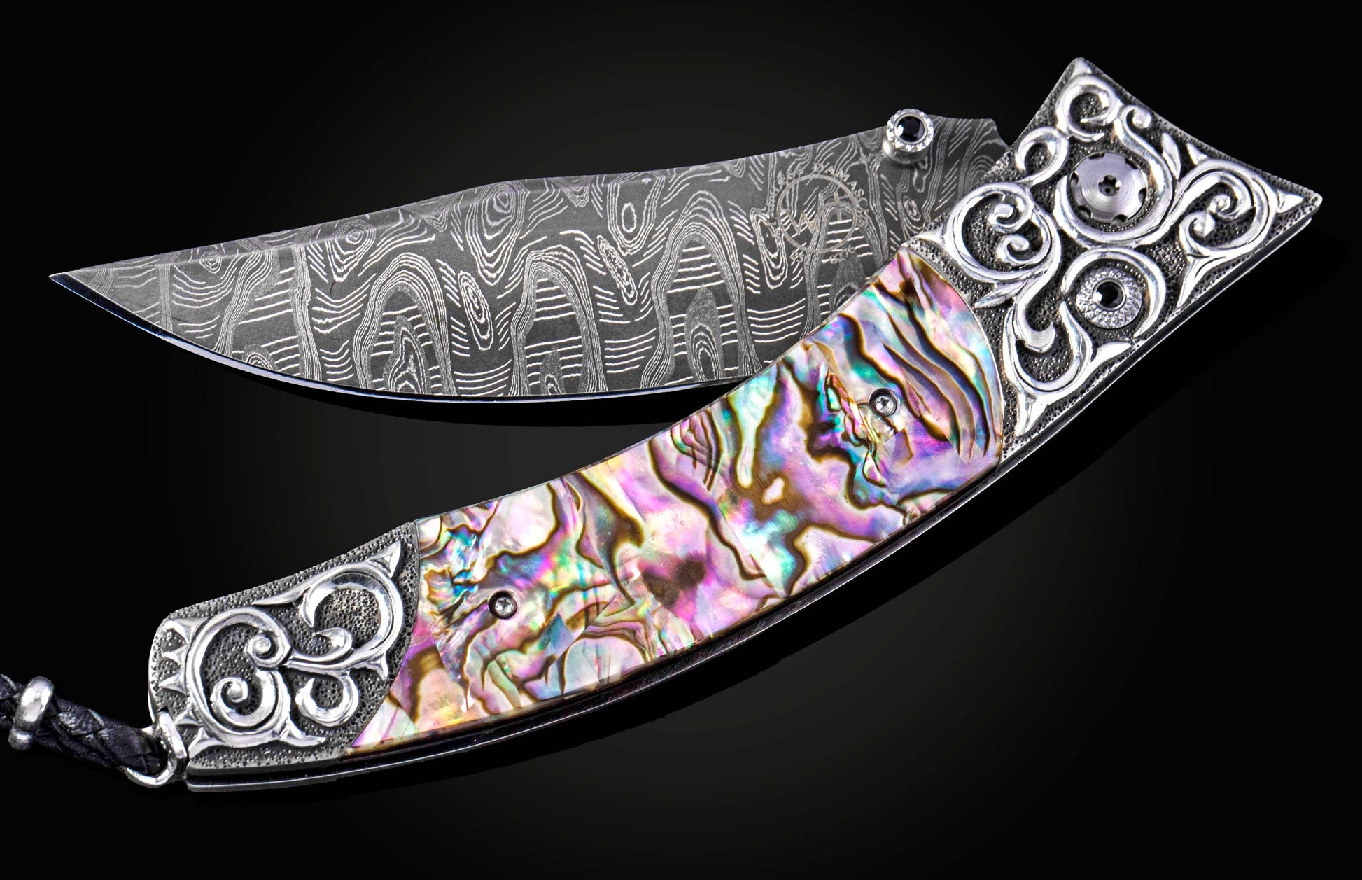 Decorative knife with ornate handle and abalone shell inlay on a black background