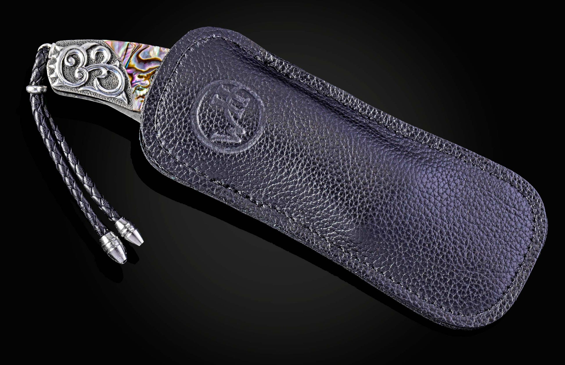Knife with decorative handle in a black leather sheath on a dark background