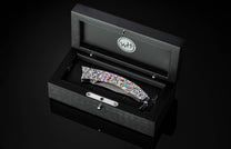 Decorative pocket knife in a black box with WH logo on a dark background