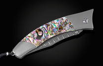 Foldable knife with abalone shell handle on a black background