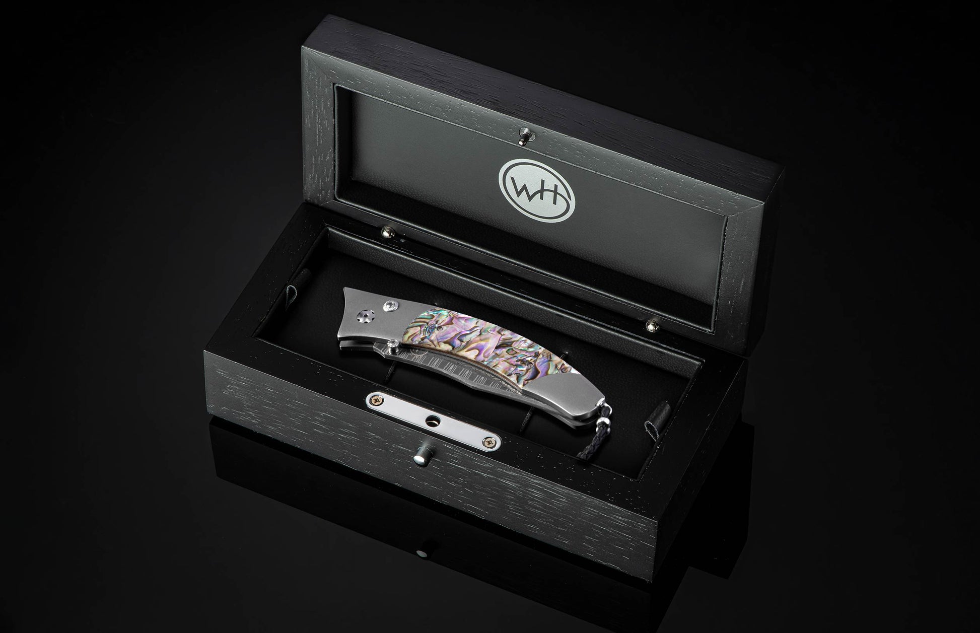 Foldable knife with abalone shell handle on a black background