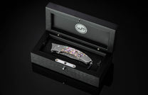 Foldable knife with abalone shell handle on a black background