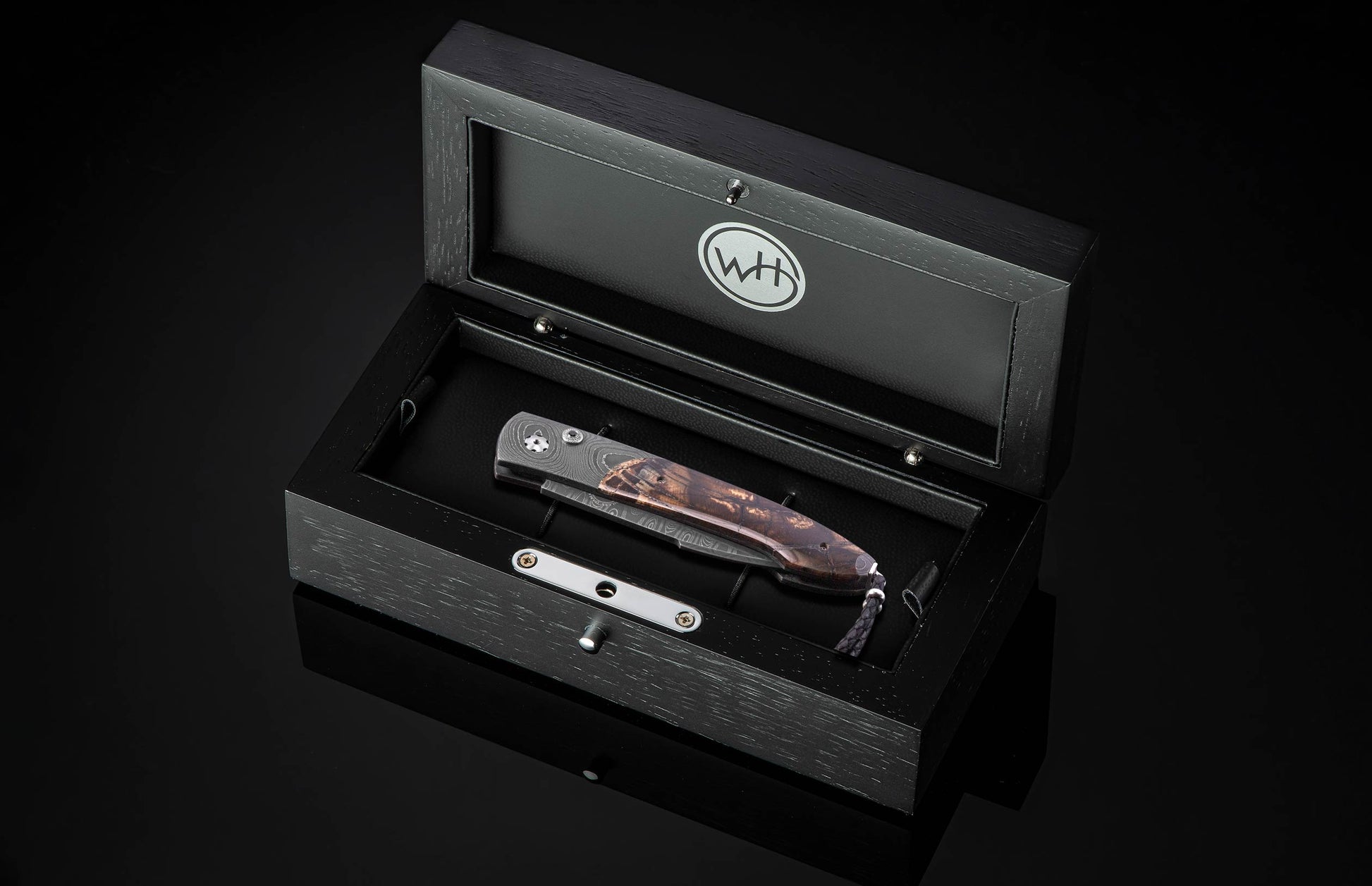 Pocket knife in a wooden display case with WH logo.