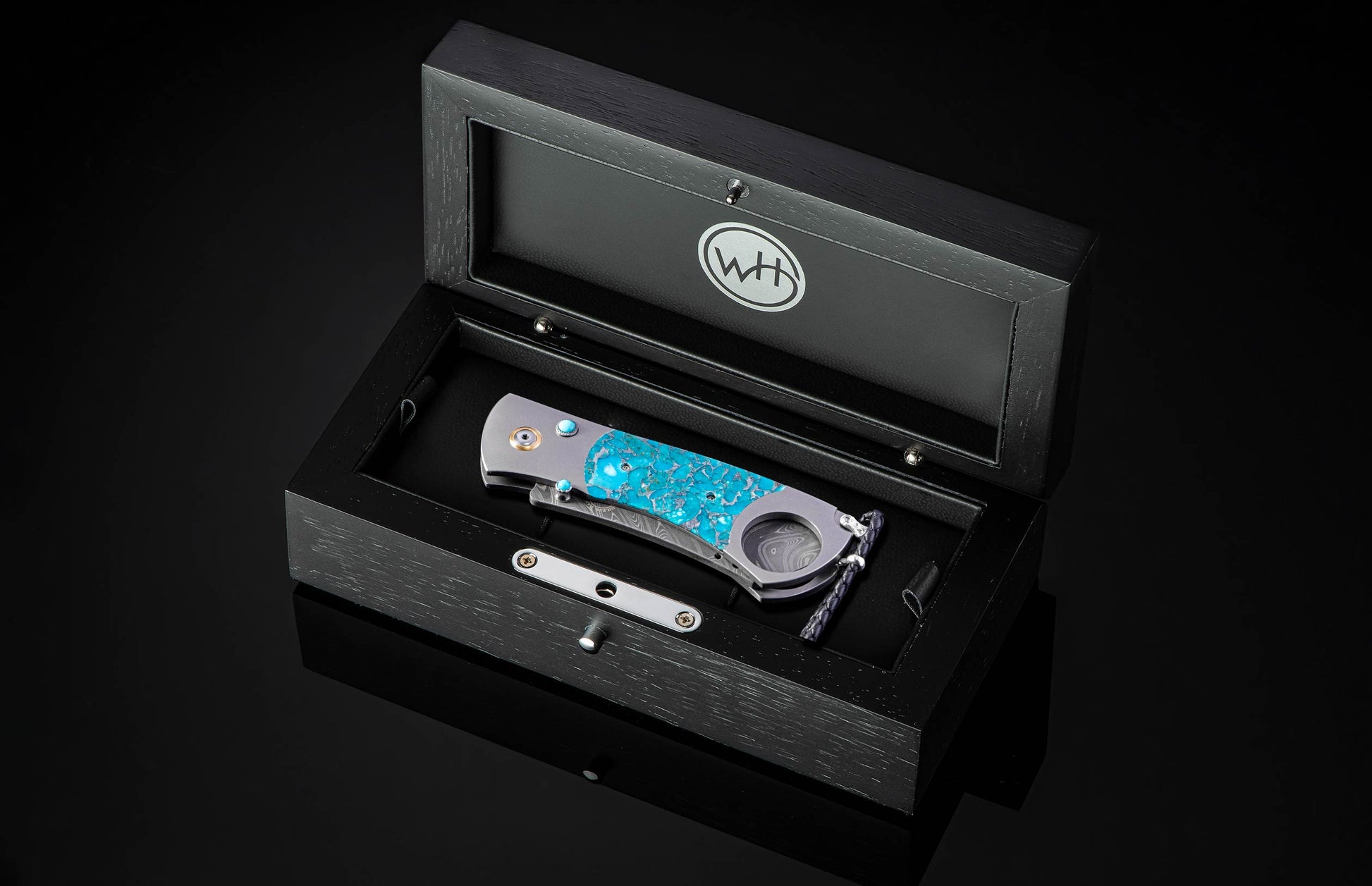 William Henry cigar cutter with turquoise handle and damascus blade on a dark background