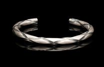 Silver bracelet with a textured design on a black background