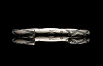 Silver bracelet with textured design on a black background