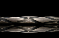 Close-up of a textured silver bracelet surface with a black background