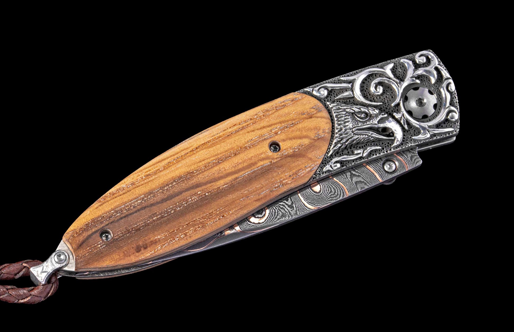 Decorative folding knife with wooden handle and damascus steel blade on a black background