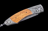 Decorative folding knife with wooden handle, silver-toned metal with pebbled texture, engraved eagle and stars, and a Damascus blade.