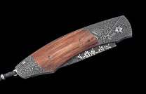 Folding knife with reddish-brown wooden handle, dark gray Damascus steel bolsters, and floral etching on the folded blade.
