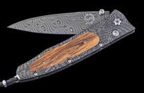 Handmade folding knife with wooden handle and damascus steel blade on a black background