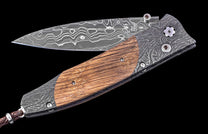 Folding knife with wooden handle and Damascus steel blade on a black background