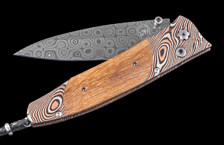 Folding knife with wooden handle and patterned blade on a black background