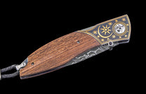 Folding knife with wooden handle and decorative metal blade on a black background