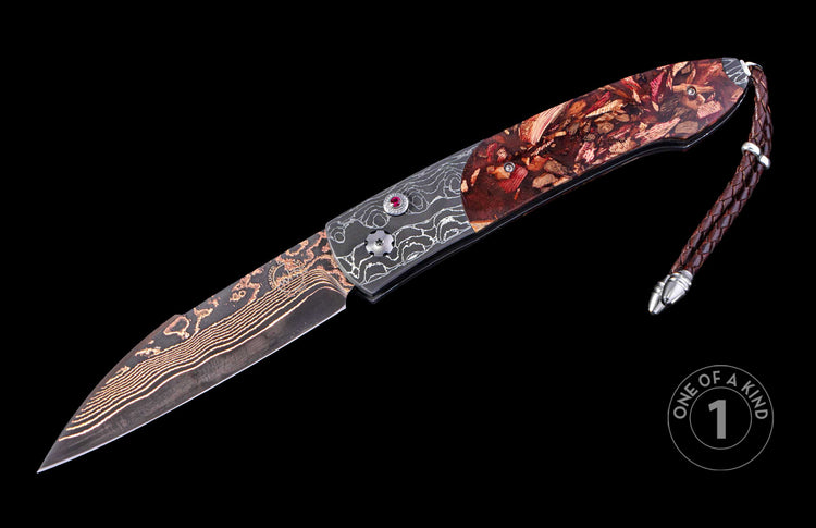 Red wood chip automatic knife with a wavy copper Damascus blade, dark grey bolster with white swirls, red gemstone, and a brown braided leather lanyard.