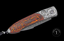 Folding knife with orange and black swirled handle, ornate silver bolsters, Damascus blade, and black braided lanyard.