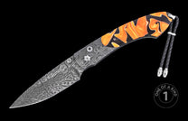 Damascus steel knife with orange and black marbled handle by custom artisan, featuring intricate wave patterns, silver hardware, and braided lanyard, side view on black background